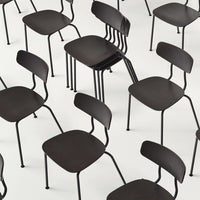 Black modern chairs with minimalist design, featuring sleek curves and a matte finish, arranged in a dynamic pattern.