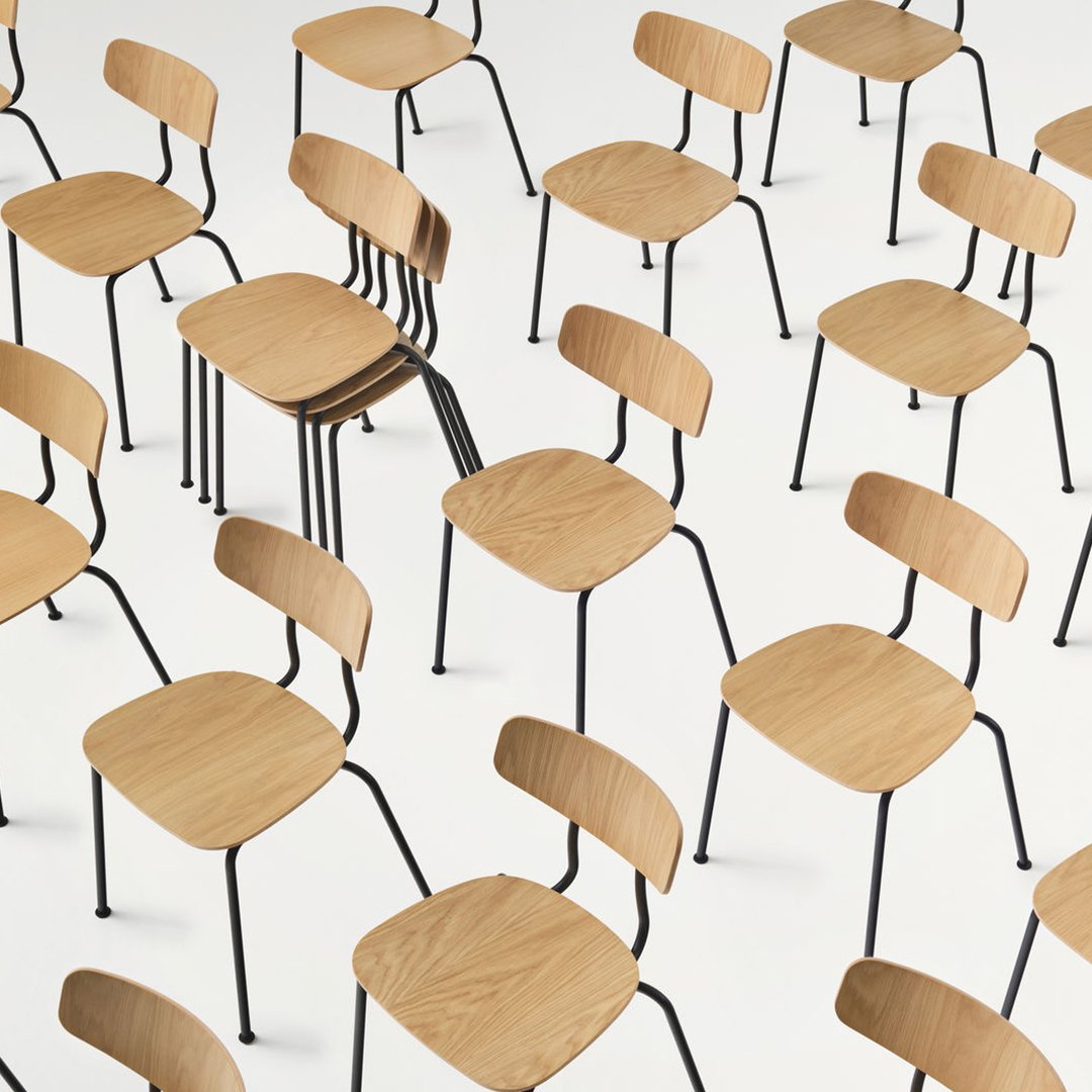 Minimalistic oak chairs with black metal legs, featuring a uniform arrangement on a white background.