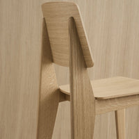 Natural wood chair with a light oak finish, featuring smooth lines and a minimalist design against a matching wood backdrop.