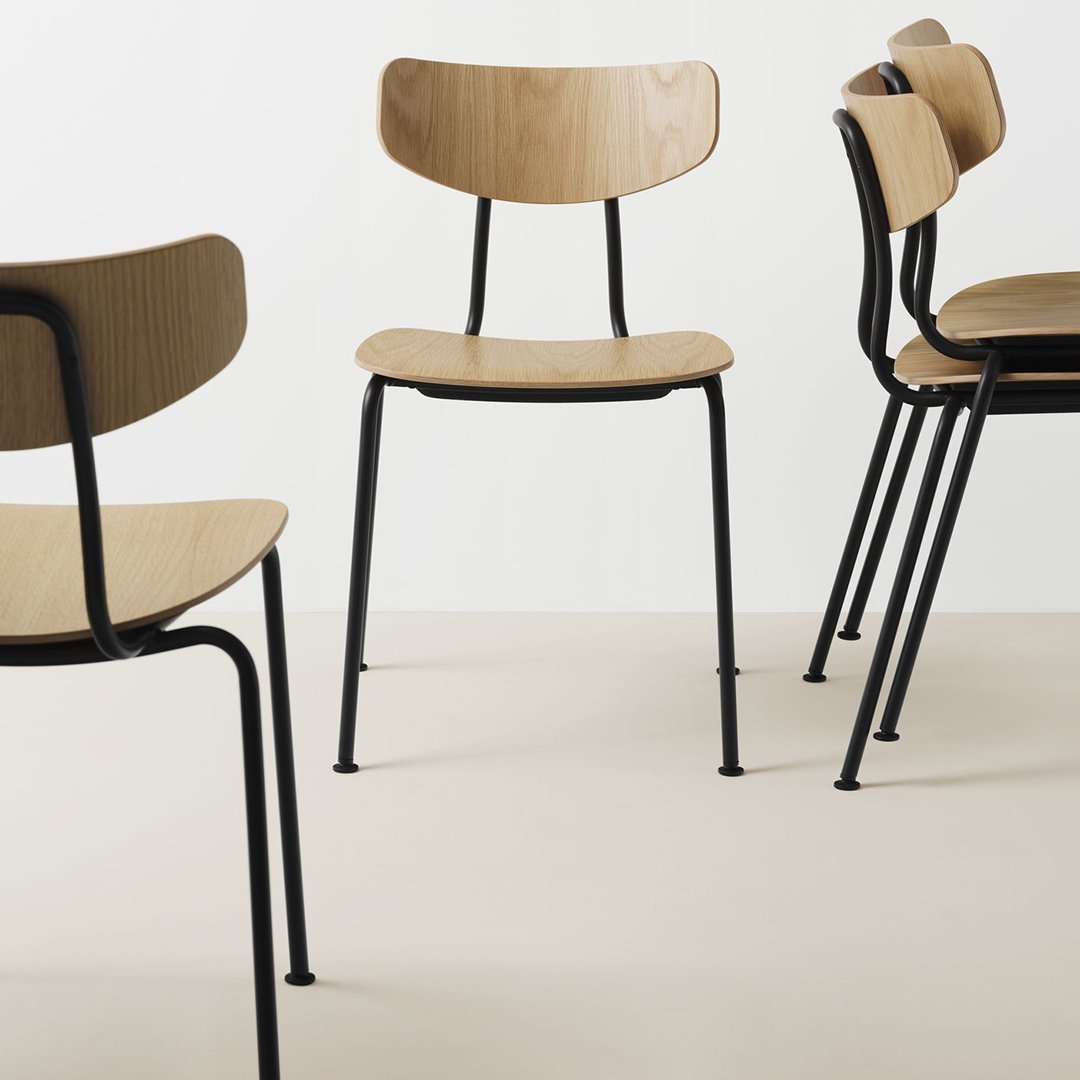 Set of four minimalist chairs featuring light wood seats and black metal legs, displayed on a neutral background.