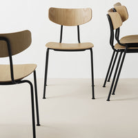 Set of four minimalist chairs featuring light wood seats and black metal legs, displayed on a neutral background.