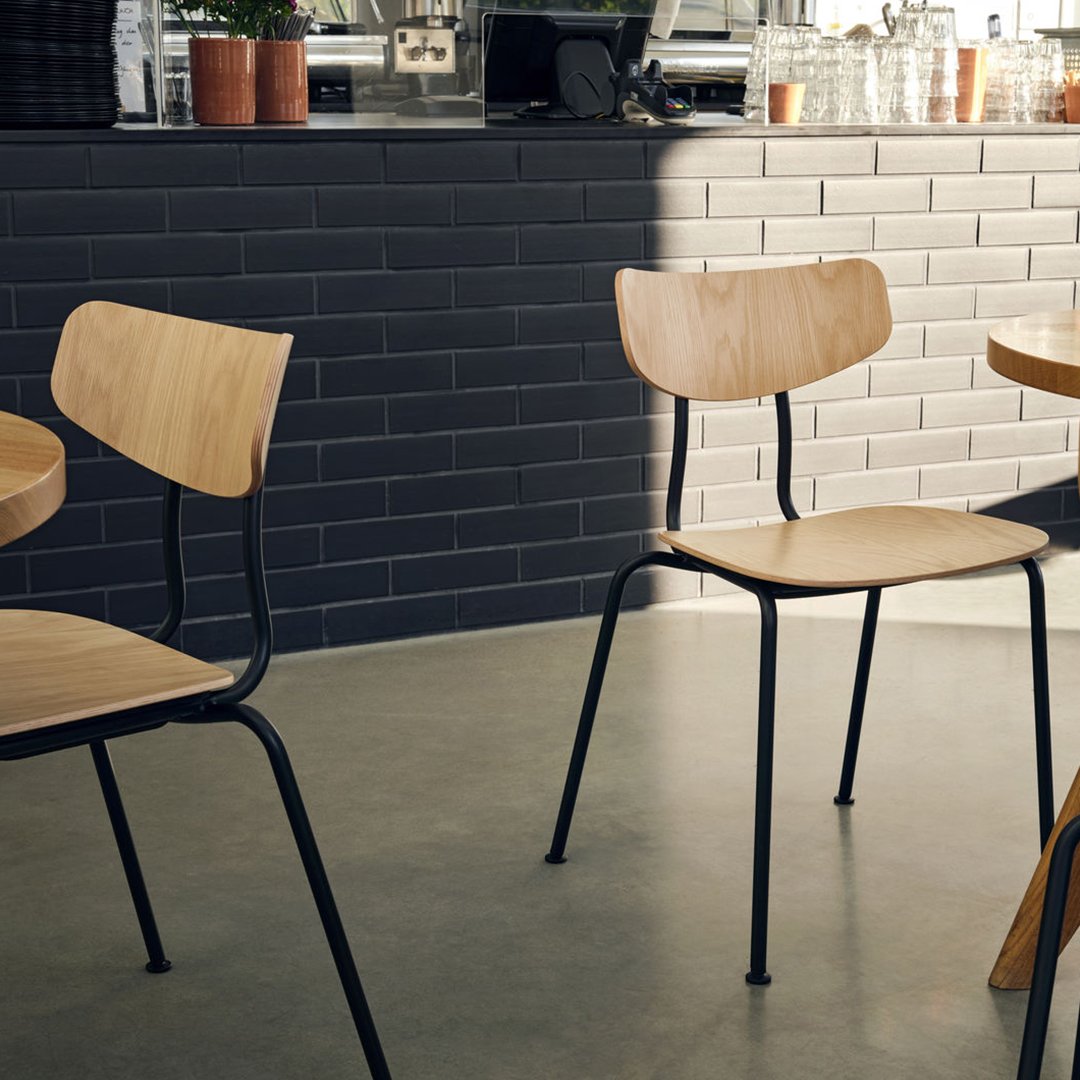 Natural wood chairs with sleek black metal frames, set against a stylish gray tile backdrop. Modern and minimalist design.