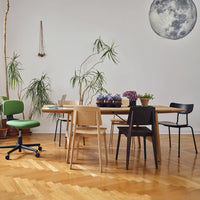 "Modern dining set featuring natural wood tones, green chair, black and light wood chairs, and vibrant purple flowers."