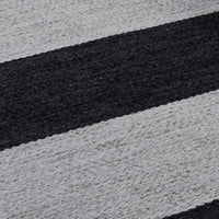 Black and gray striped pattern on a soft woven rug, creating a modern and stylish decor accent.