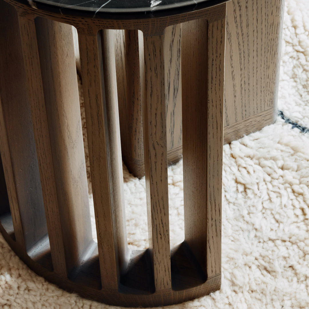 Natural wood grain with a dark marble top, featuring a textured pattern on a soft, cream-colored rug.