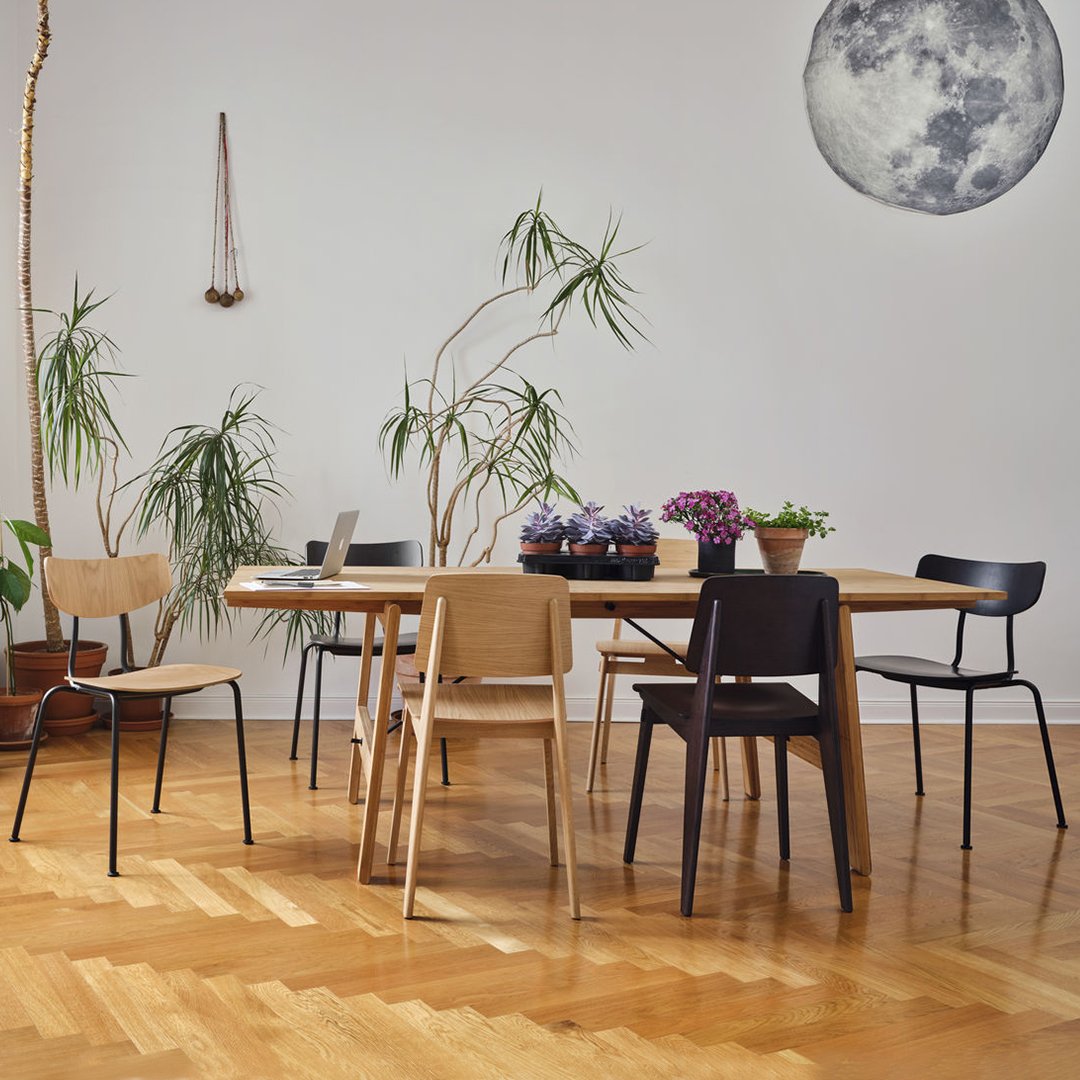 Modern dining set featuring natural wood tones, gray, black, and muted floral patterns in a bright, airy setting.