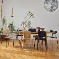 Modern dining set featuring natural wood tones, gray, black, and muted floral patterns in a bright, airy setting.