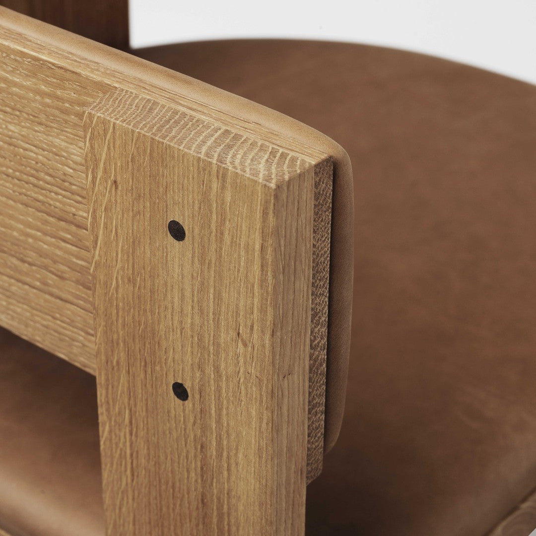 Natural wood texture with warm brown leather seat, featuring minimalistic design and simple, clean lines.