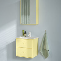 Yellow bathroom vanity with minimalist design, paired with a soft green towel against a light gray wall.