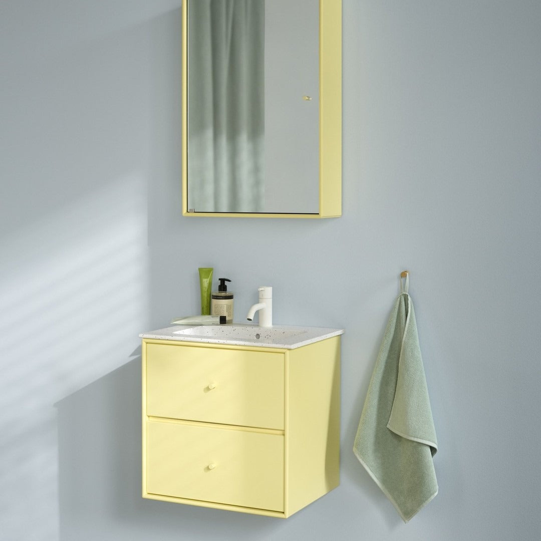 Yellow wall-mounted bathroom vanity with a matching mirror, complemented by a light green towel against a soft gray wall.