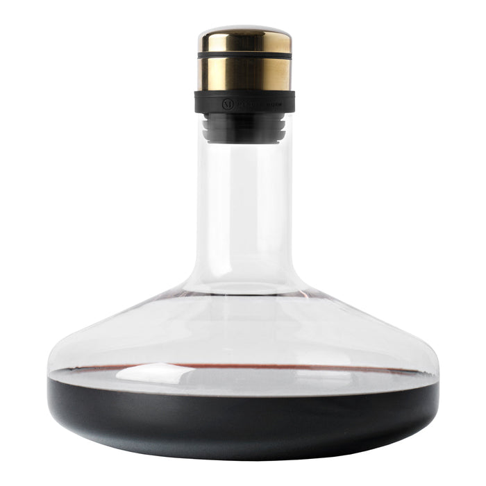 Elegant clear glass decanter with a black base and gold accent on the stopper, showcasing deep red wine.