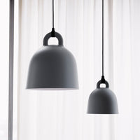 Gray pendant lamps with smooth finishes, hanging against a soft, sheer white curtain background.