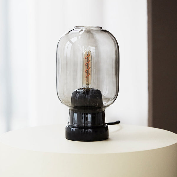 Black base lamp with a clear glass shade, featuring a vintage filament bulb for a modern yet classic look.