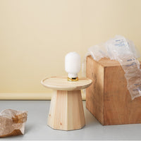 Wooden table lamp with a circular wooden base, white bulb, and neutral beige and light wood tones.