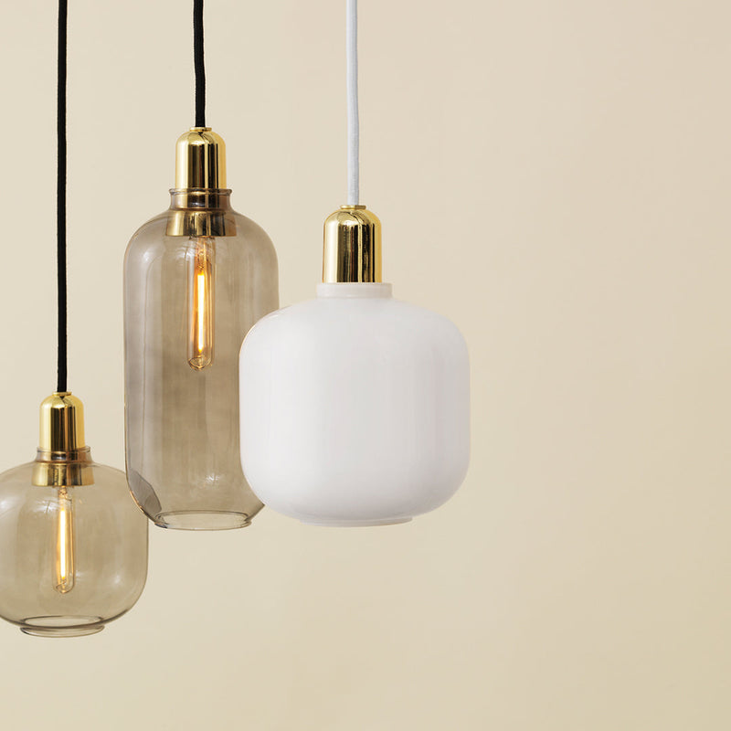 Three pendant lights featuring clear glass, frosted white, and gold accents against a soft beige background.