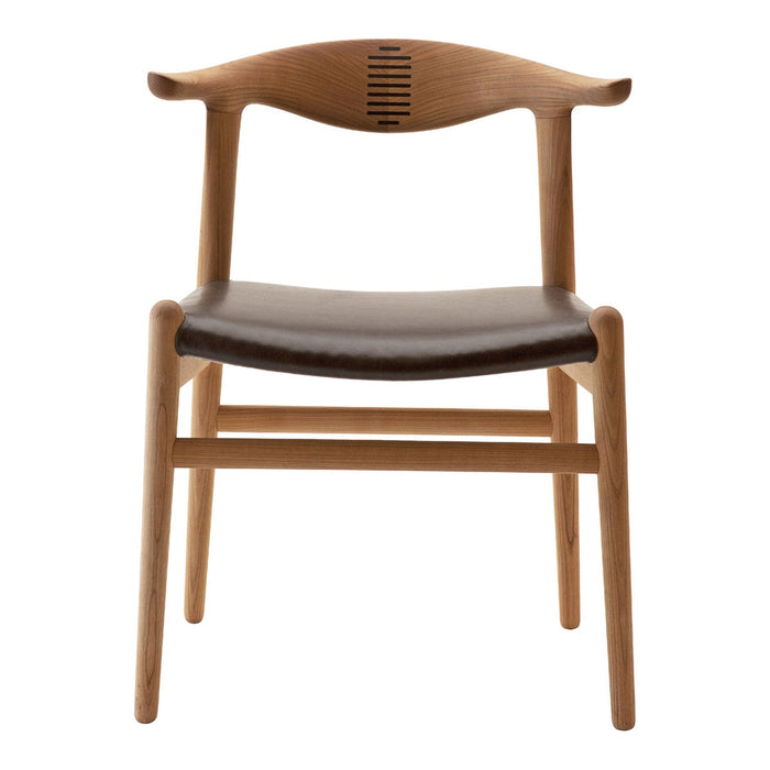 Light wooden chair with a brown leather seat, featuring a unique backrest design and minimalist style.