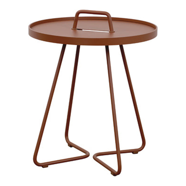 Rust-colored round side table with a handle and minimalist geometric metal legs. Sleek and modern design.