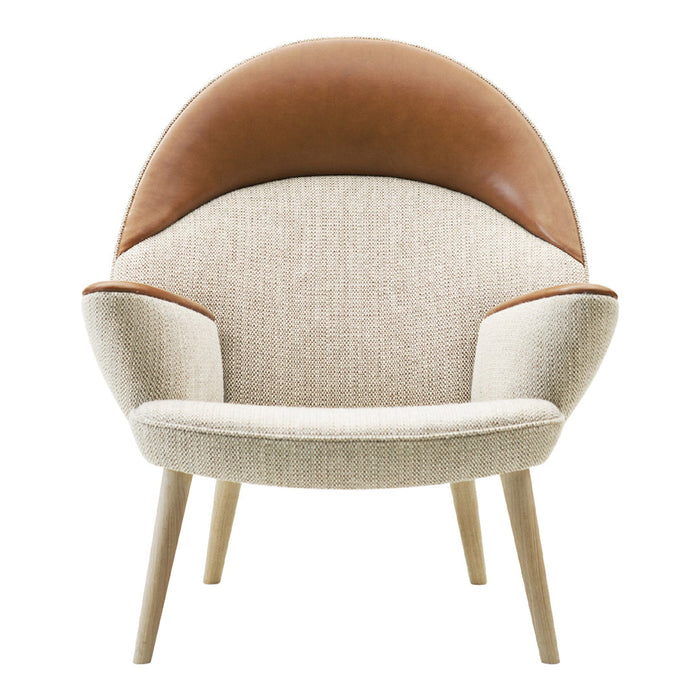 Cream and tan armchair with a curved design and textured fabric, featuring a stylish leather backrest.