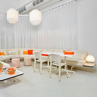 Modern lounge area featuring soft cream sofas, vibrant orange cushions, and minimalist white decor.