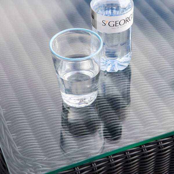 Clear glass on a textured, woven black tabletop with water in a glass and bottle.