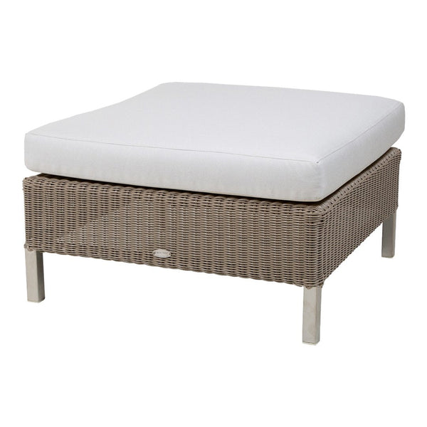 Beige woven wicker ottoman with a crisp white cushion, perfect for outdoor or indoor decor.