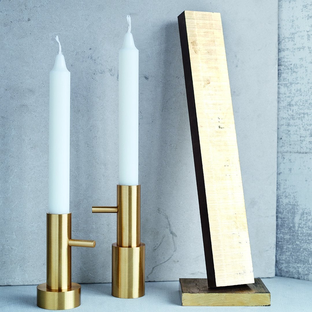 Elegant gold candle holders with white candles, paired with a sleek gold and dark wood geometric design.