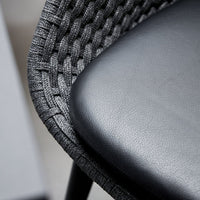 Close-up of a chair with woven backrest and leather seat.