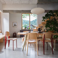 Modern dining room featuring natural wood tones, red accents, neutral gray walls, and soft ambient lighting.