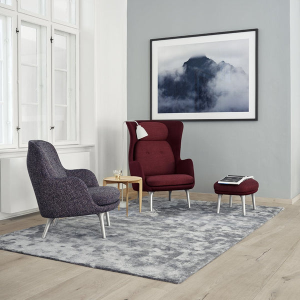 Plush burgundy and gray armchairs on a textured gray rug with a modern, abstract wall art in a stylish room.