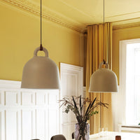 Two beige pendant lamps hang against a soft yellow wall, complemented by cream curtains and a minimalist table setting.