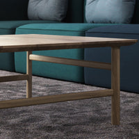 Wooden coffee table with a natural finish, set against a teal couch and a textured gray carpet.