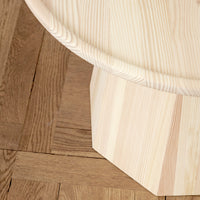 Light wood coffee table with smooth round top and textured octagonal base, featuring natural beige and cream tones.