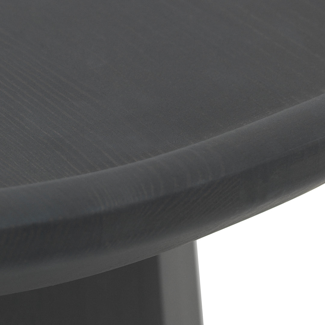 Close-up of a smooth, round table edge in a sleek dark gray finish with subtle wood grain pattern.