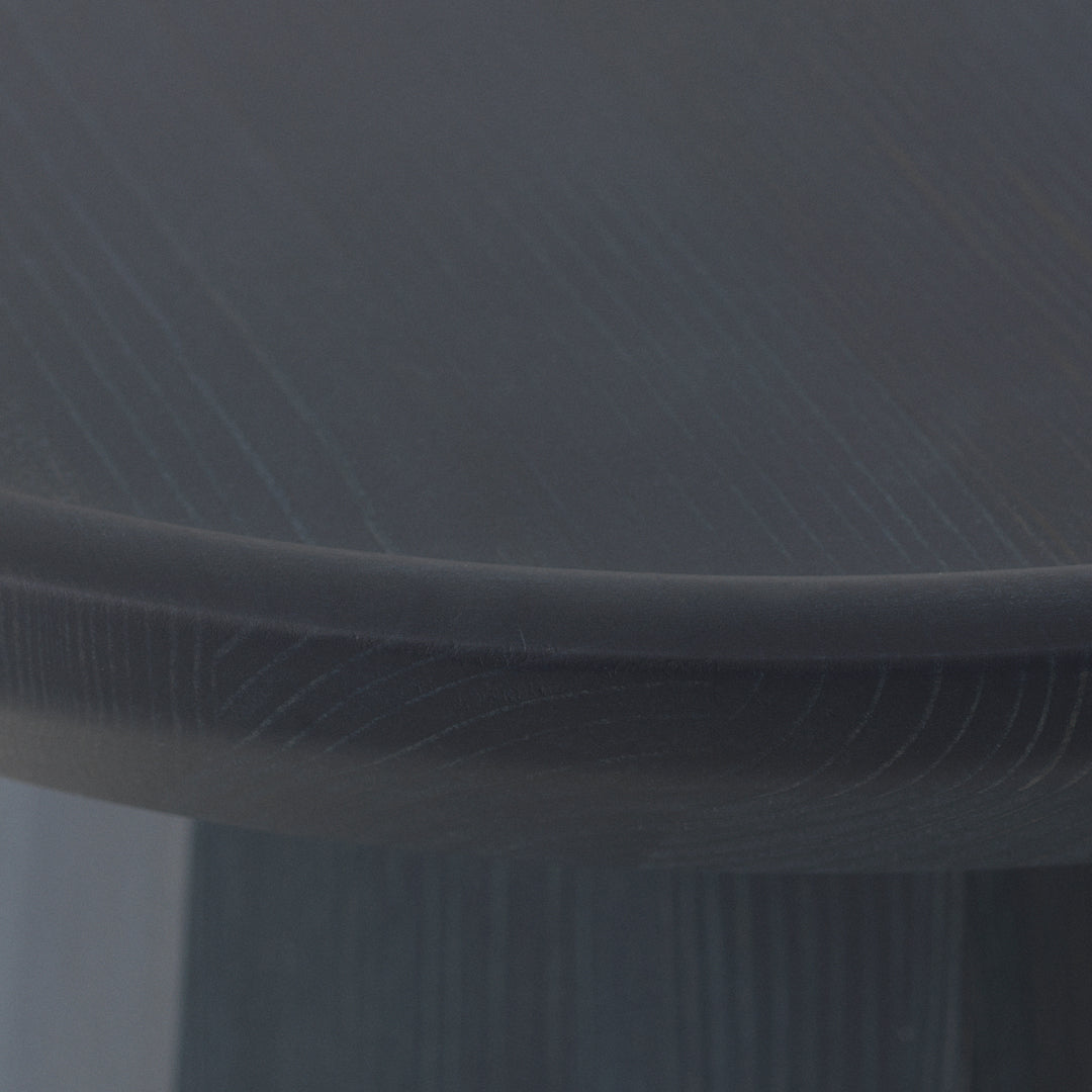 Close-up of a round table surface in dark gray with subtle wood grain pattern texture.