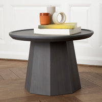 Gray octagonal side table with a smooth surface, featuring stacked colorful decor—orange, white, and yellow accents.
