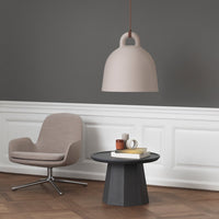 Soft beige pendant lamp with a smooth finish, paired with a modern gray chair and dark geometric table.