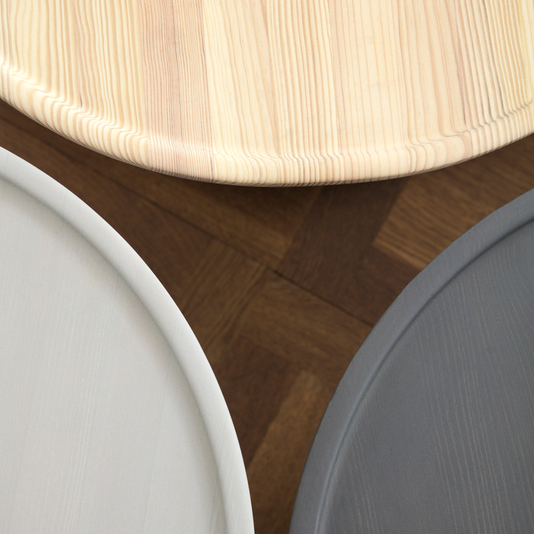 Natural wood, soft gray, and crisp white plates with smooth textures and circular shapes on a dark patterned background.