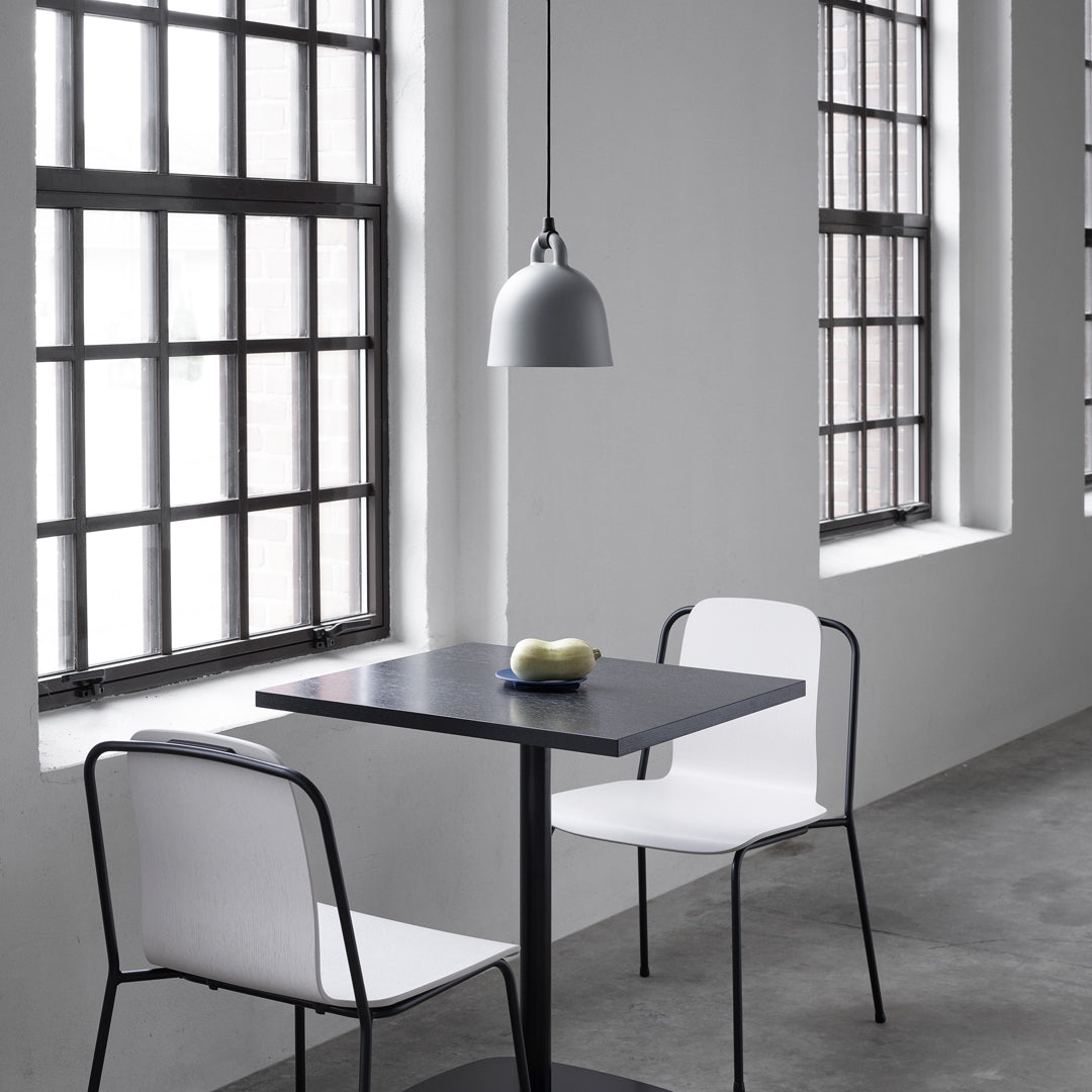 "Modern black table with white chairs in a minimalist gray interior, featuring sleek lines and light patterns."