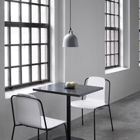 "Modern black table with white chairs in a minimalist gray interior, featuring sleek lines and light patterns."