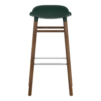Green upholstered bar stool with wooden legs and chrome footrest, featuring a smooth, minimalist design.