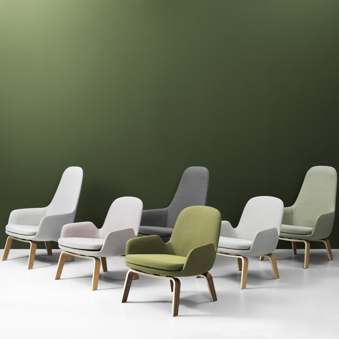 Set of modern chairs in gray, white, pink, and green, with natural wood legs against an olive green backdrop.