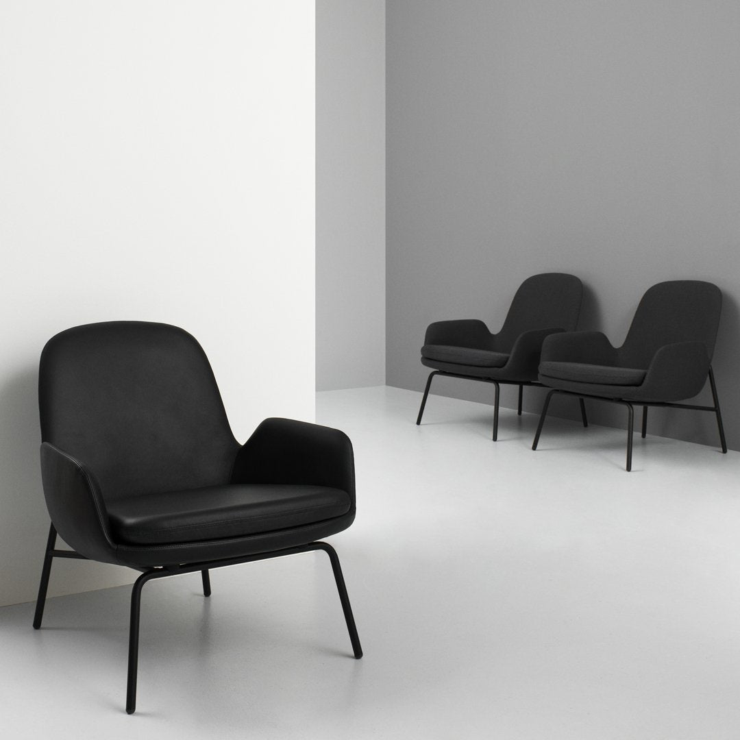 Black upholstered chair with a minimalist design, featuring sleek black metal legs against a light gray and white backdrop.