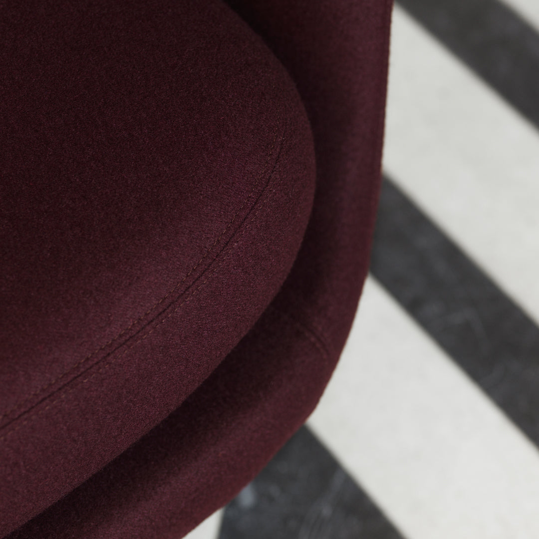 Burgundy upholstered chair resting on a black and white striped rug.