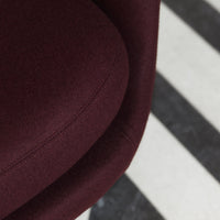Burgundy upholstered chair resting on a black and white striped rug.