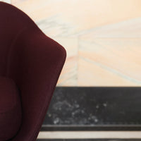 Burgundy upholstered chair against a soft marble background with subtle beige and gray veins.