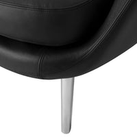 Black leather chair detail with sleek silver metal leg, showcasing a modern, minimalist design.