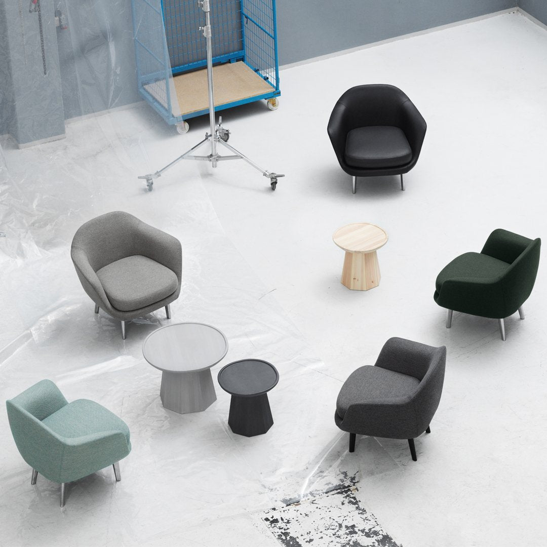 Modern armchairs in gray, green, and black with a light wood table, set against a minimalistic gray background.