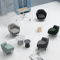 Modern armchairs in gray, green, and black with a light wood table, set against a minimalistic gray background.