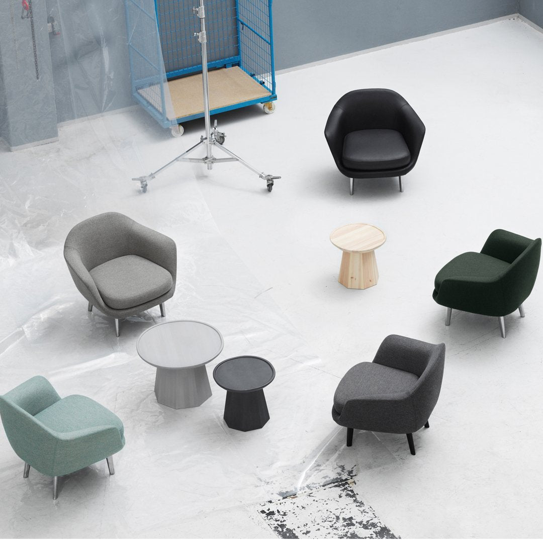 Modern armchairs in gray, black, green, and aqua with minimalist design and various textures, arranged around sleek tables.