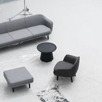 Modern gray sofa set with textured fabrics and black, round coffee table on a minimalist white floor.